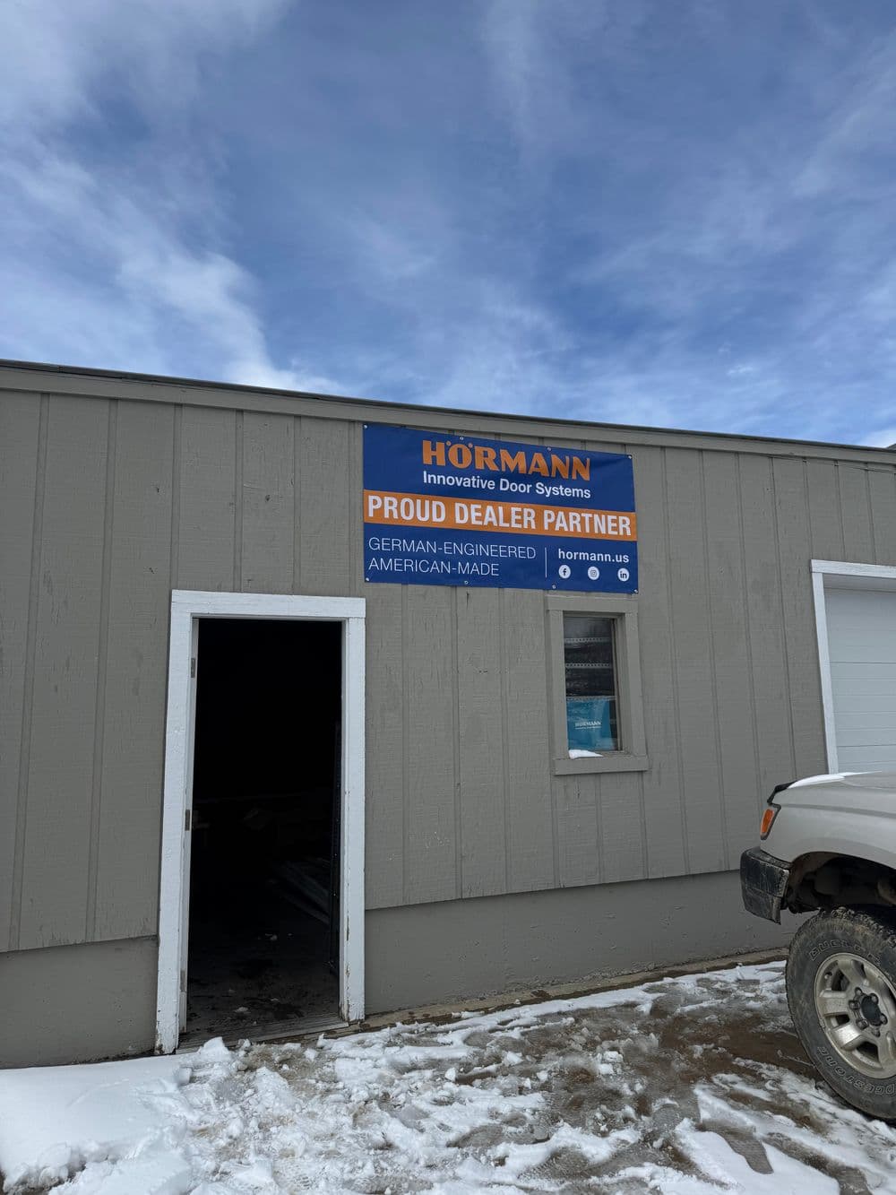 Hörmann dealership sign on a building showcasing German-engineered, American-made door systems.